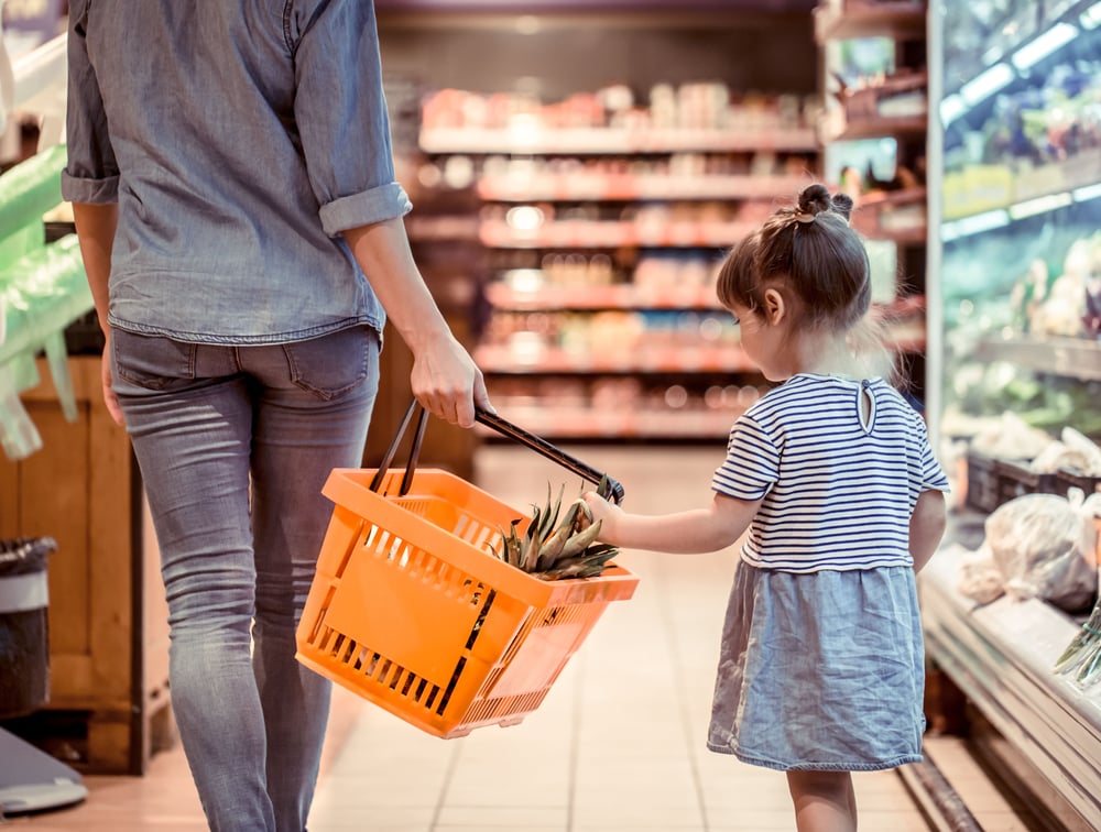 a girl grocery shopping with her mom
